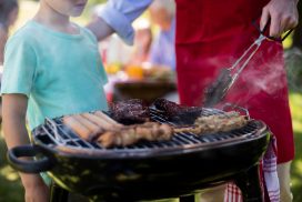 Mid section of father and son barbequing in the park during day