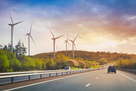 Cars going on highway in the landscape with wind propellers