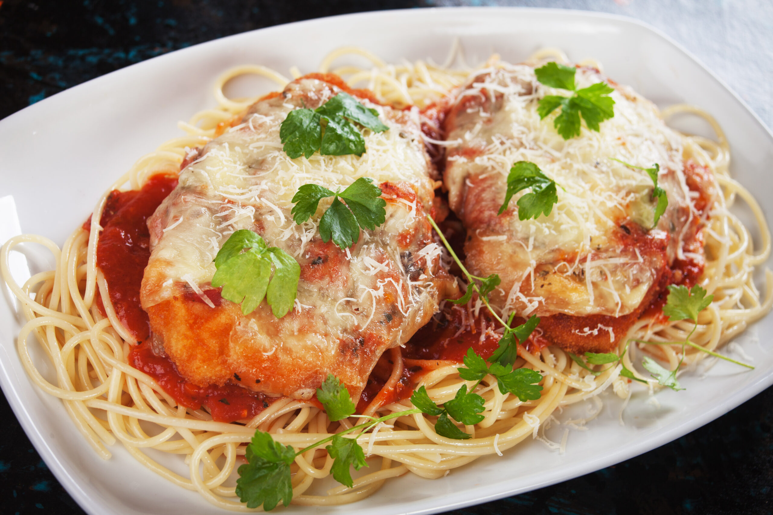 Parmesan chicken with melted cheese, tomato sauce and spaghetti pasta