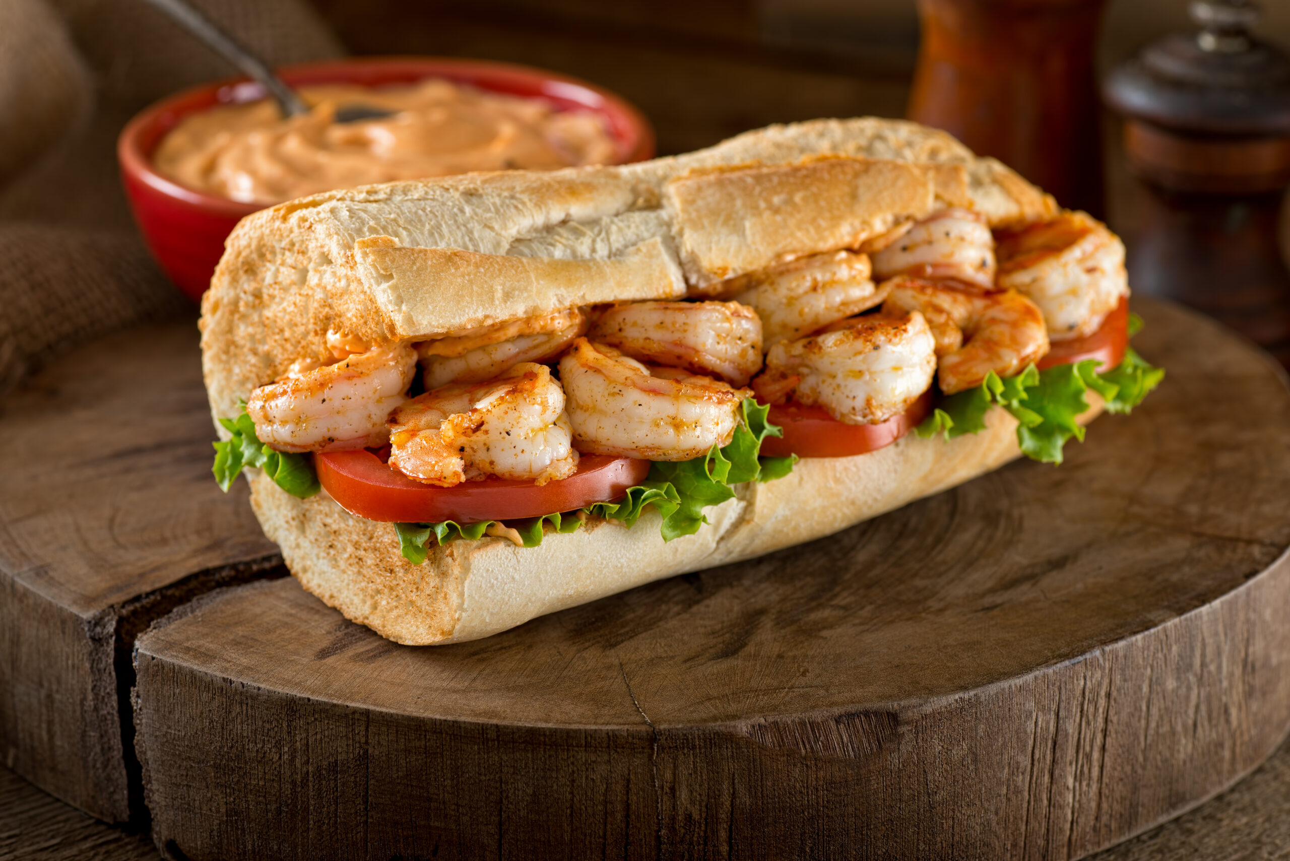 A delicious home made grilled shrimp Po Boy sandwich on baguette dressed with lettuce, tomato, and remoulade.